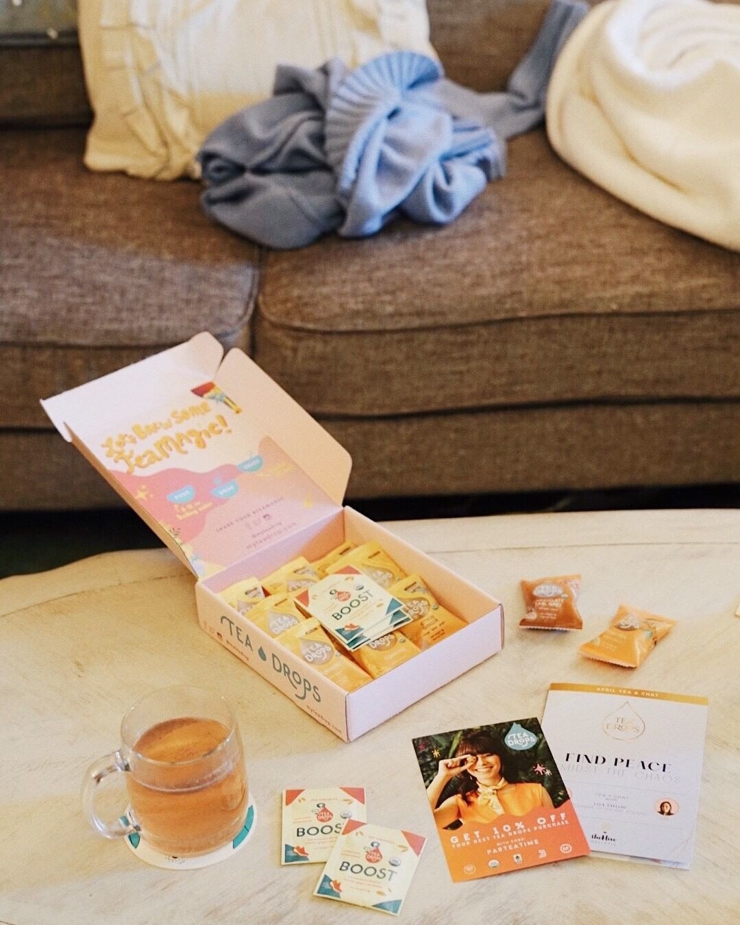 a clear glass mug of tea next to a box filled with tea bags