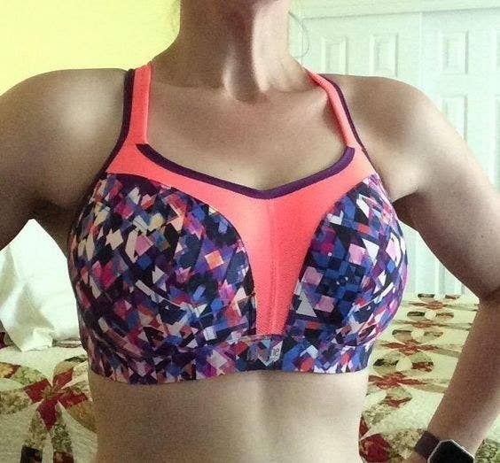 reviewer posing in pink and blue geometric sports bra