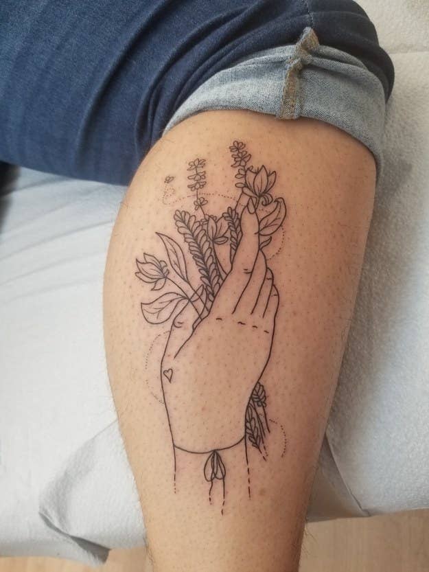 black and white line tattoo of hand holding a bouquet of flowers