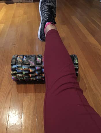reviewer rolls along calf with multicolor black foam roller