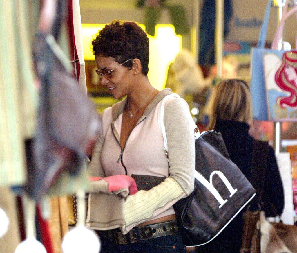 Halle Berry wearing sunglasses and carrying large black purse with an &quot;h&quot; in white lettering on the side of it.