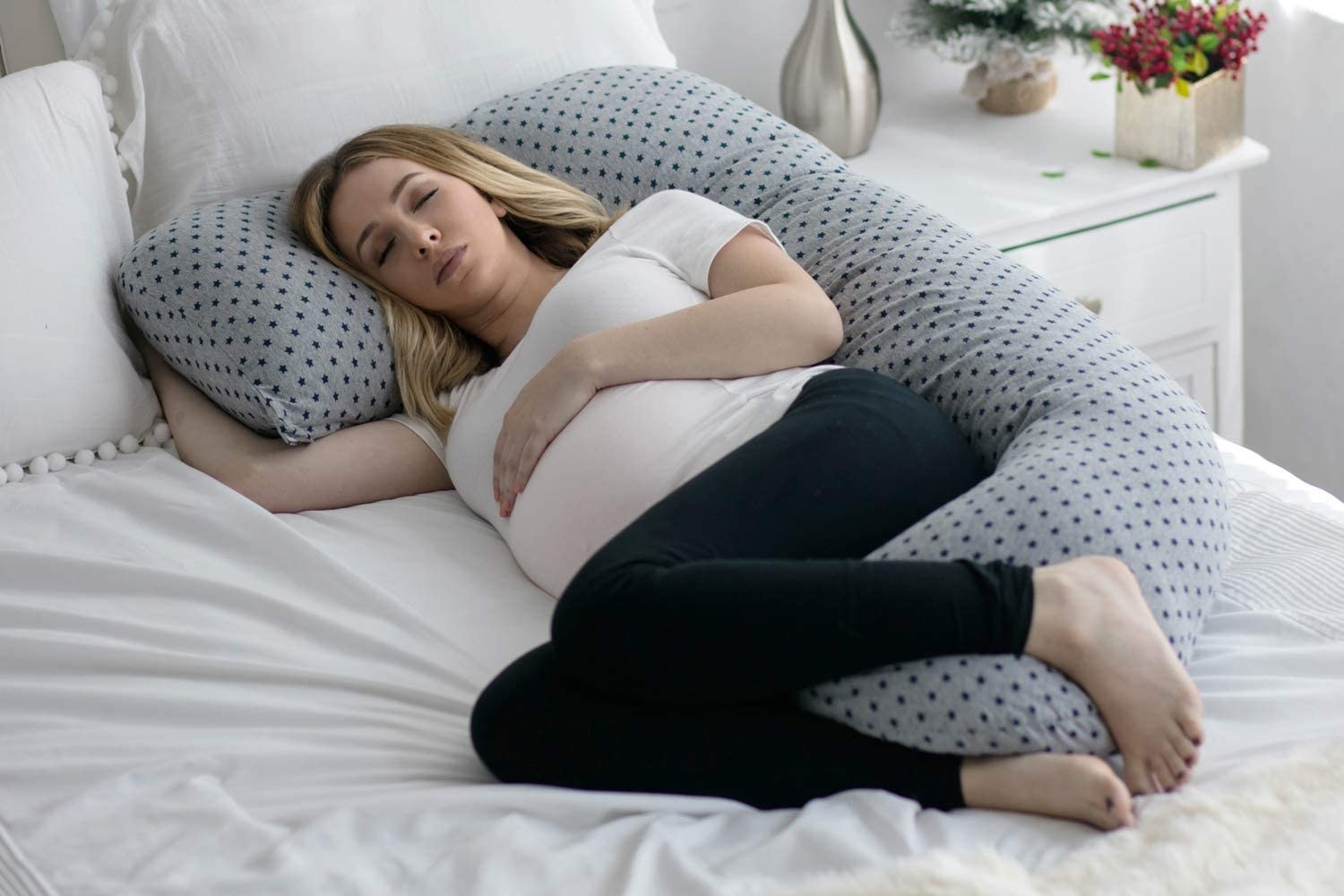 pregnant model with a C-shaped pillow supporting their back, neck, and legs