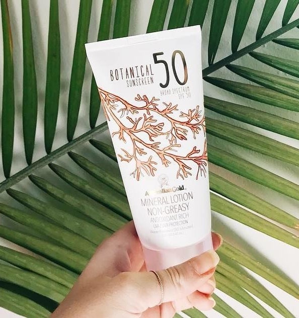 hand holding white bottle labeled "Botanical Sunscren 50 Broad Spectrum SPF"