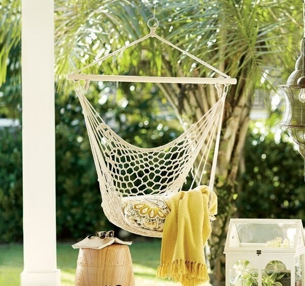 Natural wood and rope chair hammock hanging from back porch