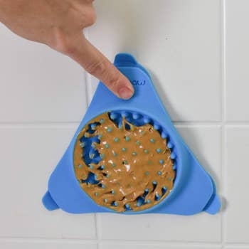 A person attaching the mat covered in peanut butter to their shower wall