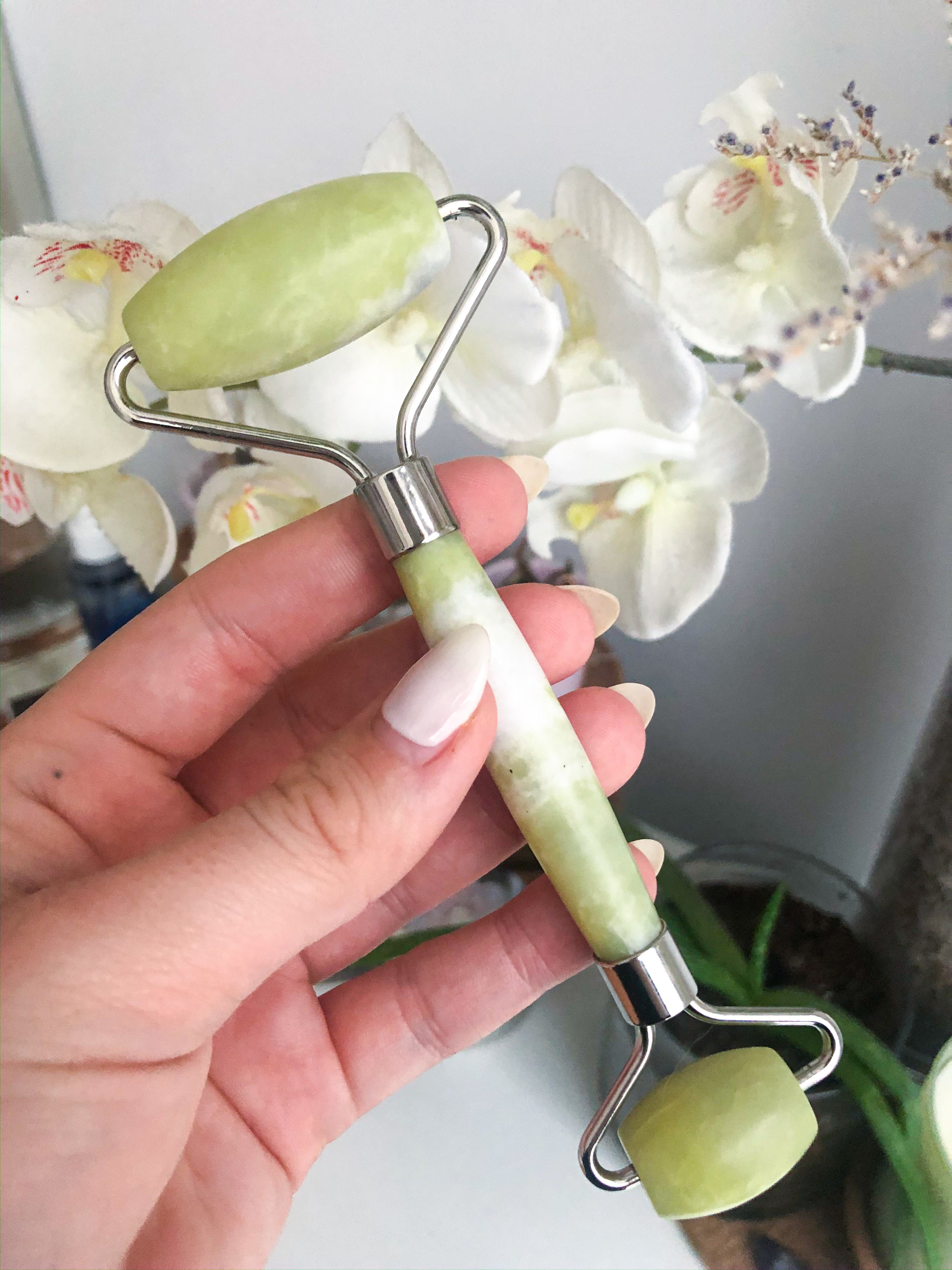 The jade roller held against a floral background