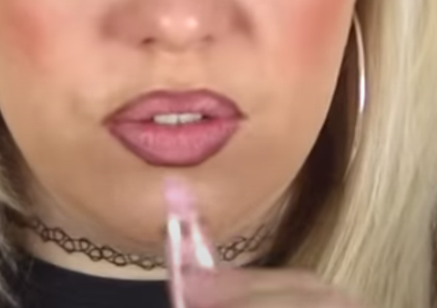 Screenshot of woman applying light lipstick with dark lip liner