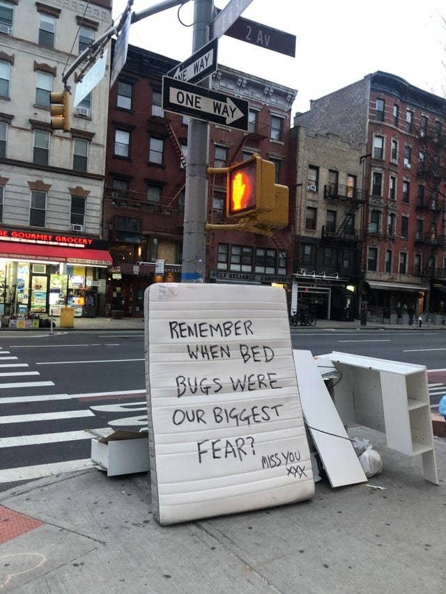 A mattress on the sidewalk with the words, &quot;Remember when bed bugs were our biggest fear? miss you xxx&quot; written on it