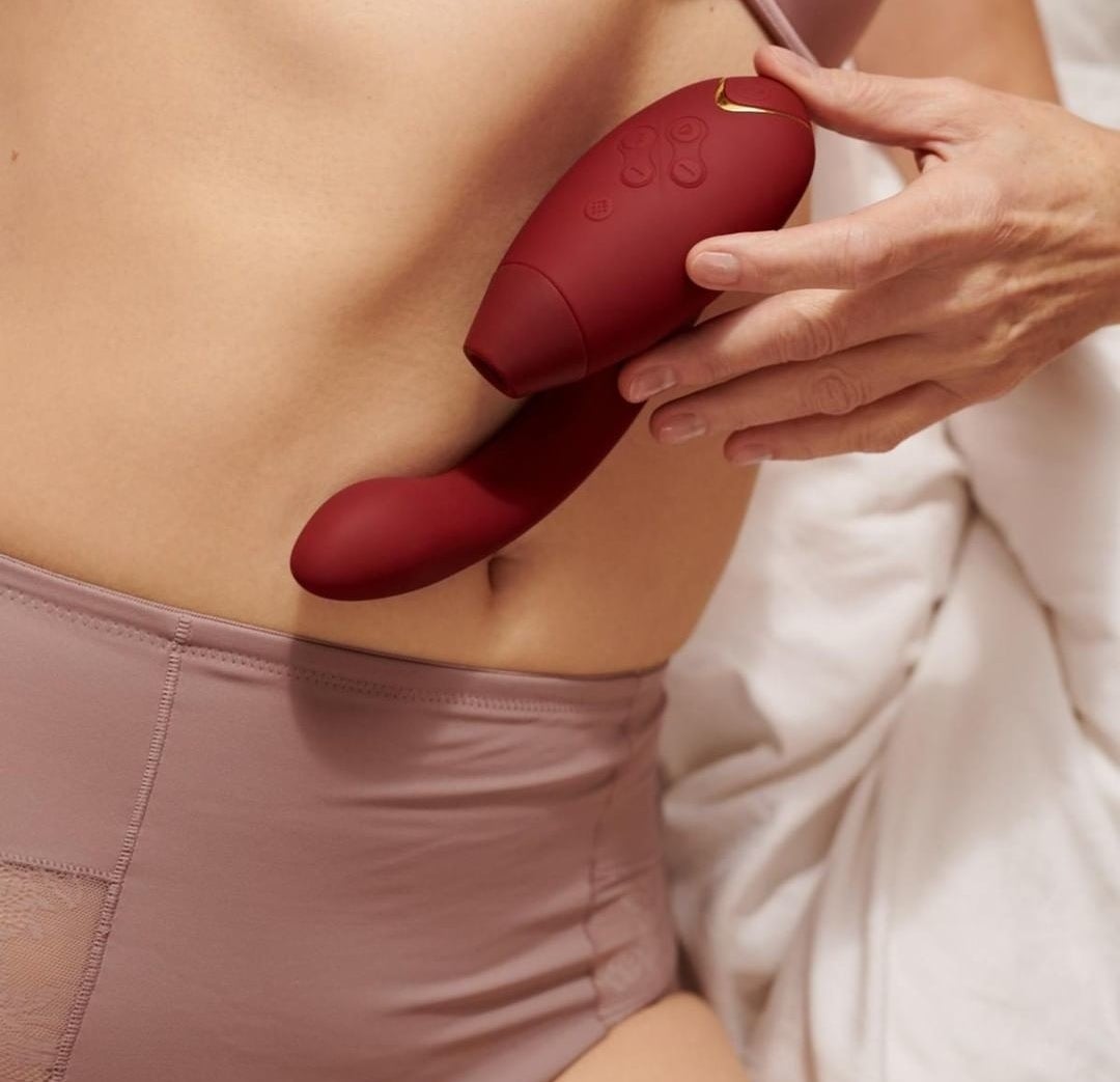 A person holding the vibrator against their stomach