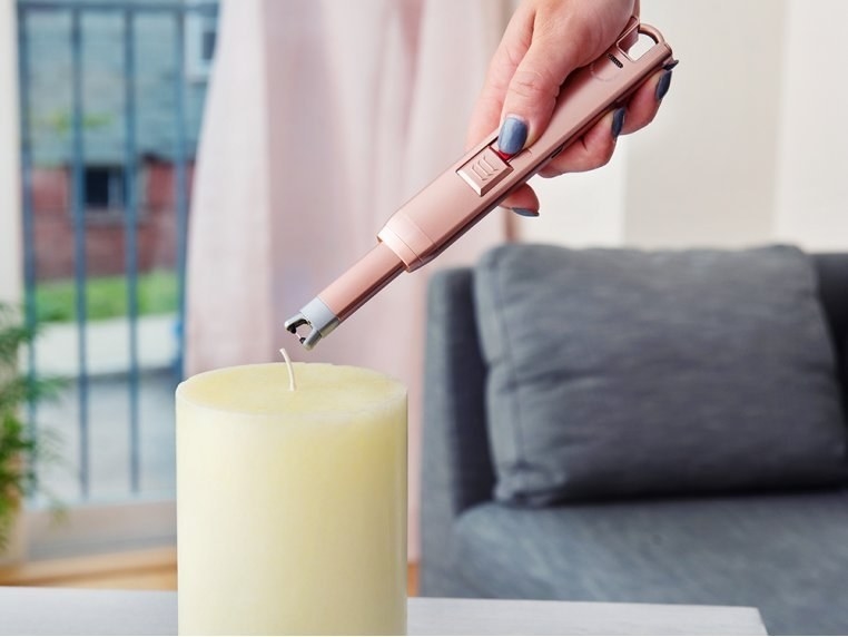 Model holding the lighter in rose gold about to light a candle