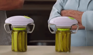 Animated Gif: older woman and a younger, buff man watch as the electric jar openers open two jars of pickles, then high-five at the end