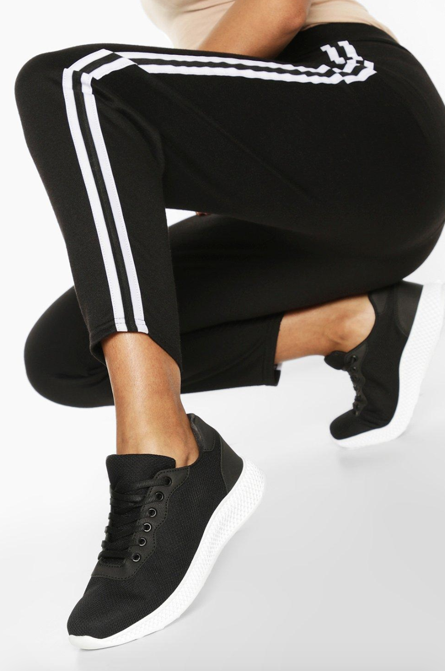 model wears black running sneakers with white bottoms