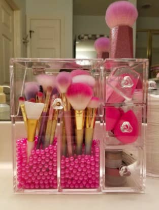 reviewer's pic of the organizer with lots of makeup brushes and sponges in it