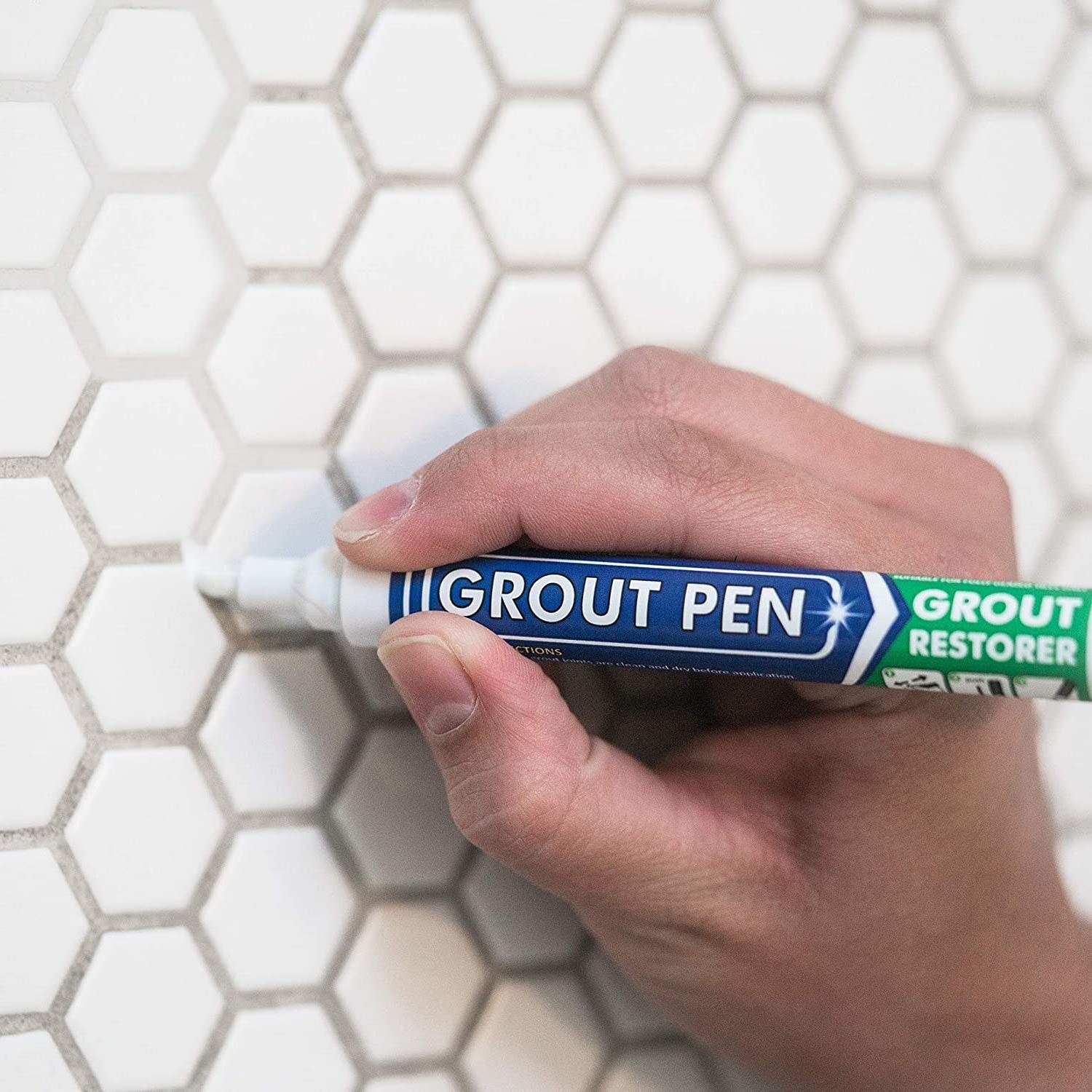 the pen cleaning grout between white tiles