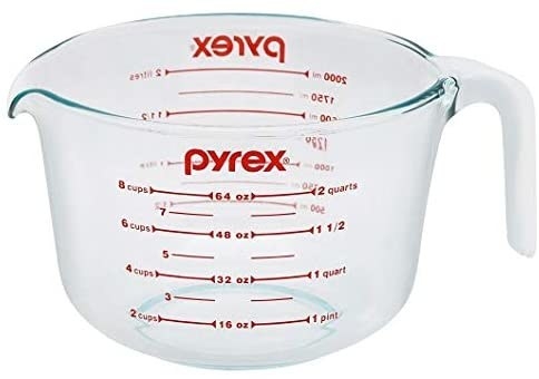 A clear glass Pyrex measuring cup with red measurements in cups and ounces on the side