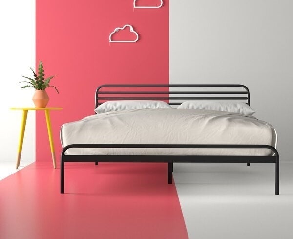 An industrial bed frame made entirely of metal piping, with rounded corners and five pipes making up the short headboard area 