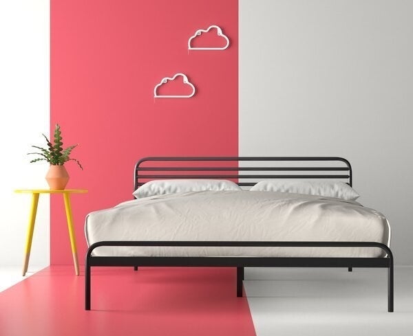 An industrial bed frame made entirely of metal piping, with rounded corners and five pipes making up the short headboard area 