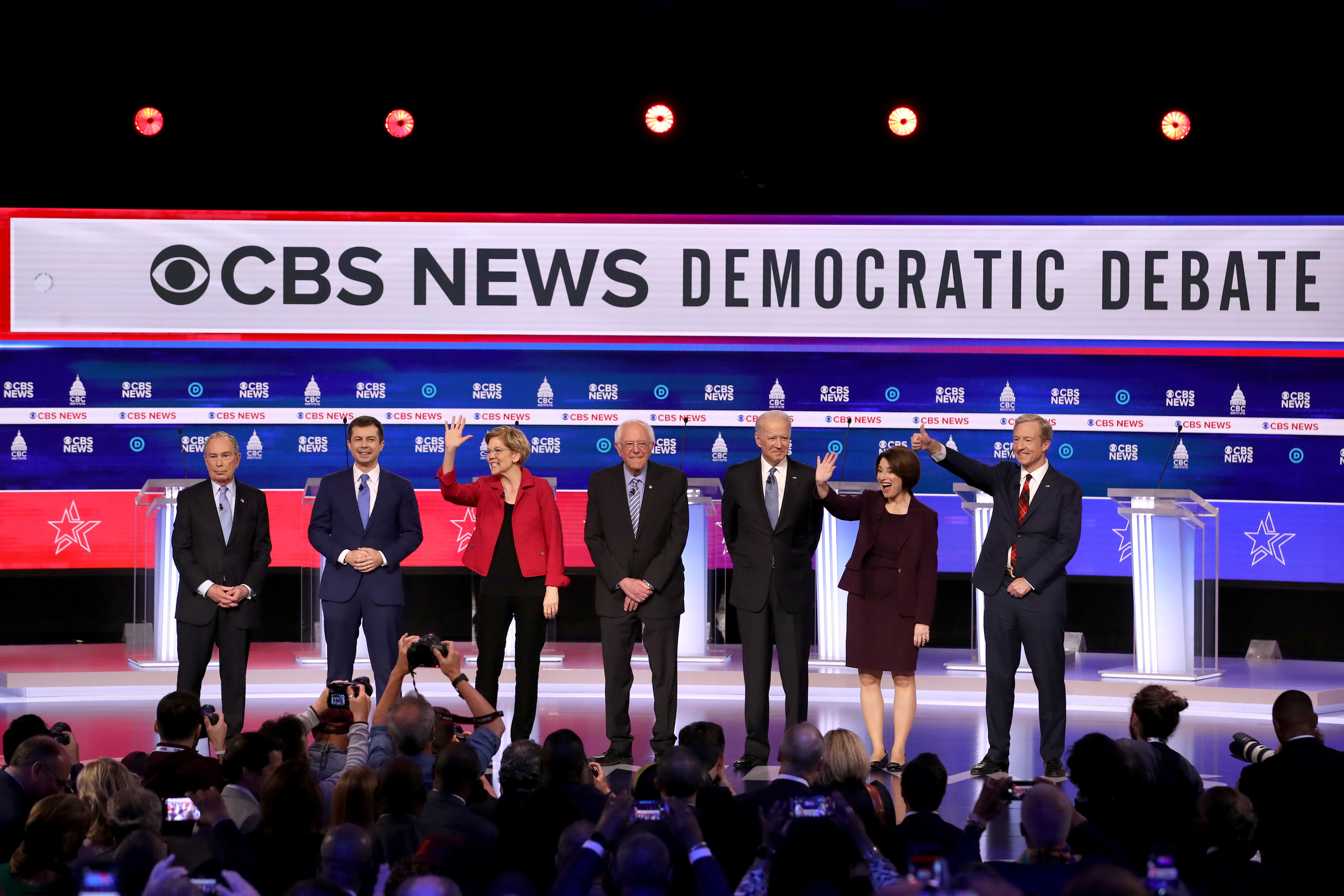 Seven Democratic presidential candidates standing on the debate stage