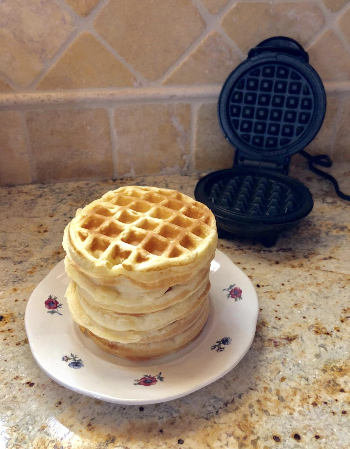 the mini singe waffle maker next to a plate with a stack of small waffles