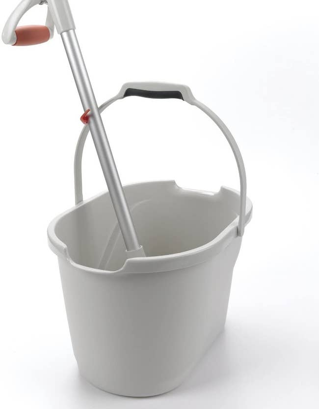 A achromatic integrative bucker with handled extended portion holding up a mop