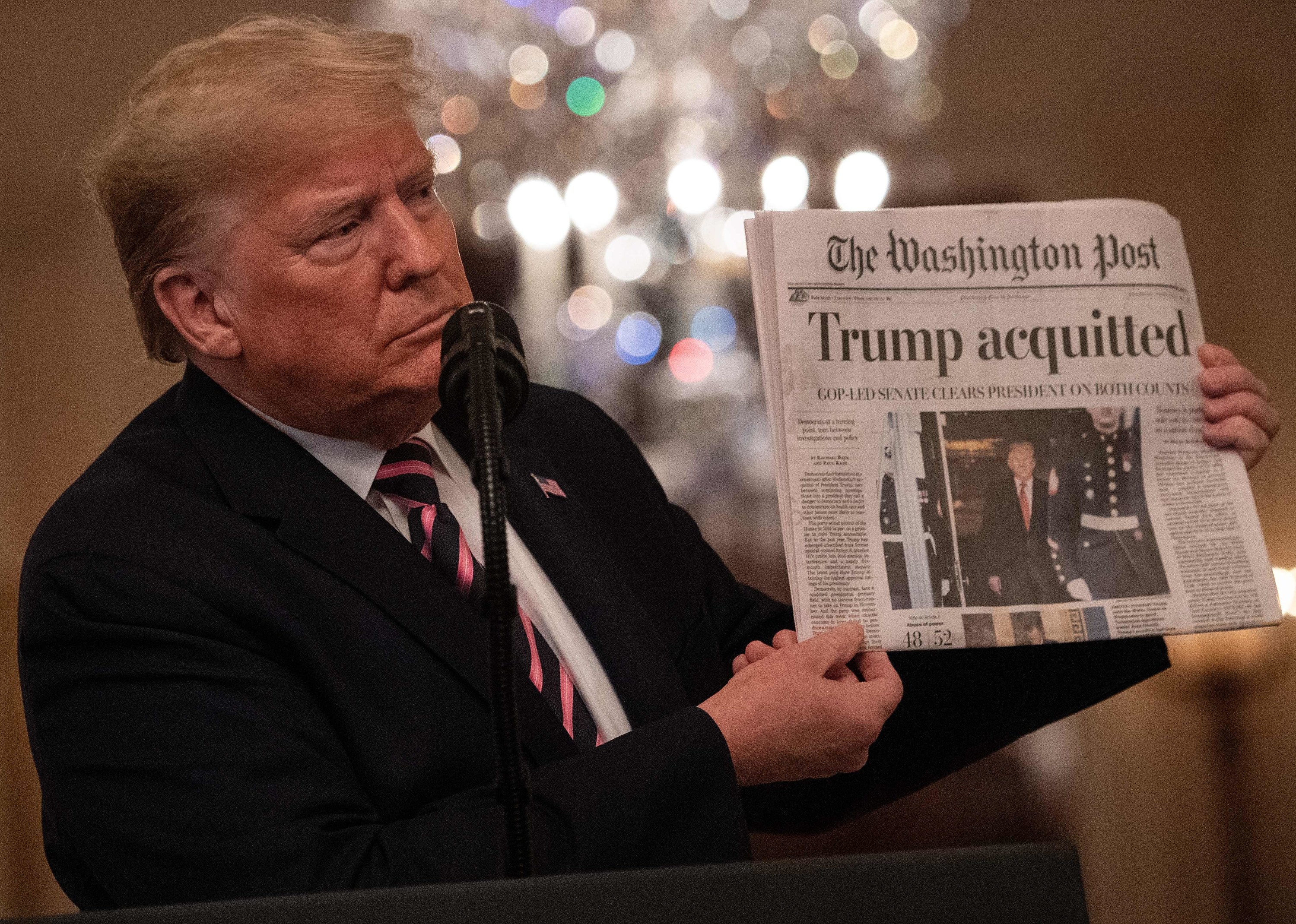 Donald Trump holding up &quot;The Washington Post&quot; front page with the headline &quot;Trump acquitted&quot;