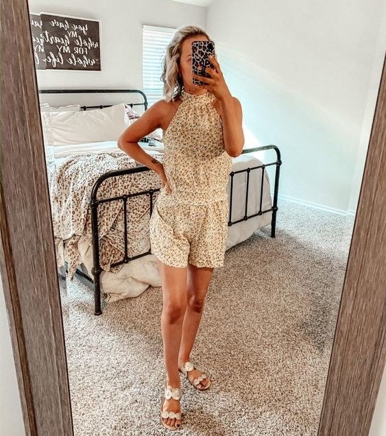 Rviewer wearing the light yellow and white floral romper with a cinched middle and halter neckline