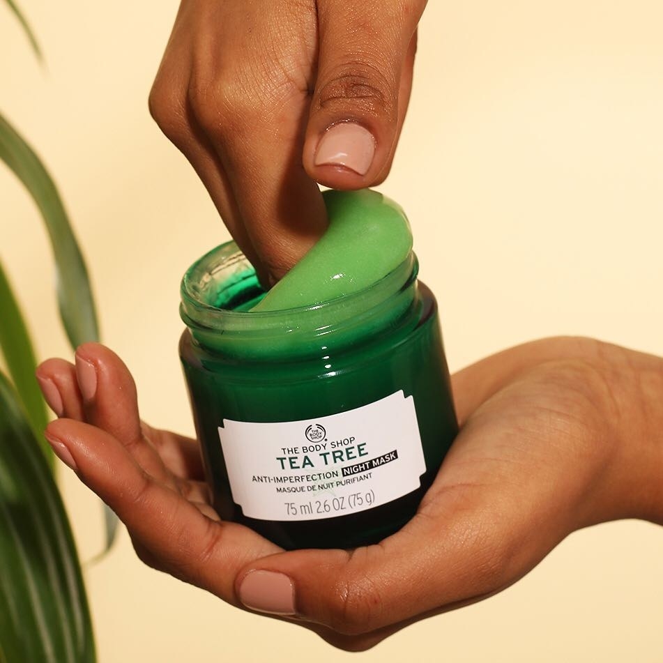 hand dipping into green jar of product