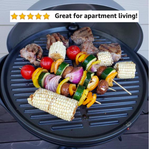 The grill with corn, steaks, and veggie kabobs cooking 