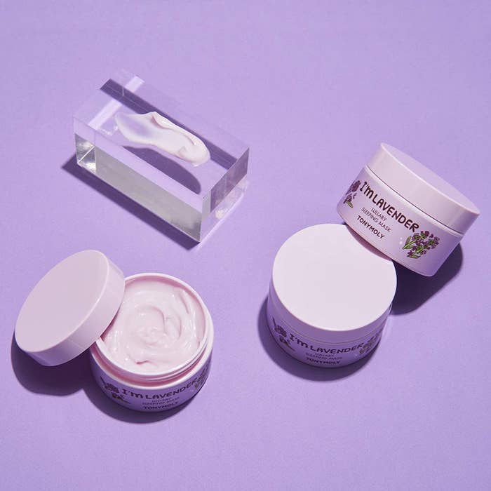 An open and two unopened jars of the mask against a purple background