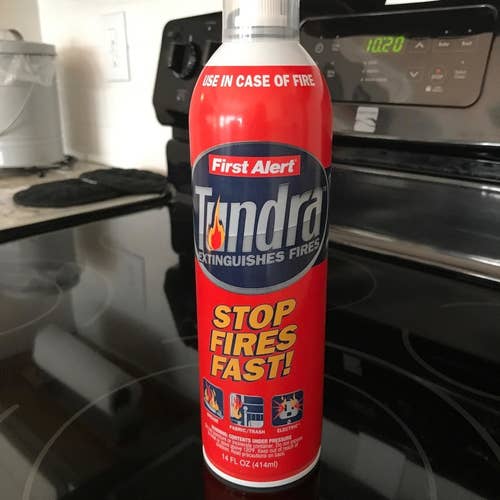 A can of Tundra brand aerosol fire spray set atop a stovetop