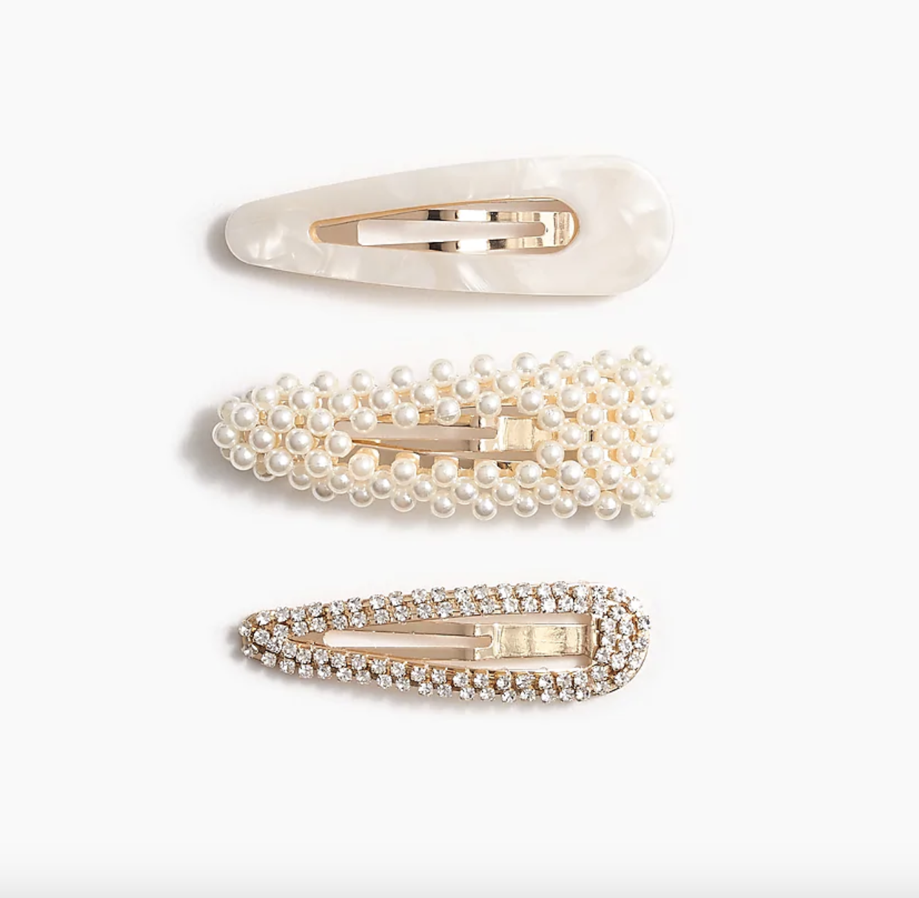 Three different-styled pearl clips — the top one plain acrylic, the middle one pearl-studded, and the third one covered in rhinestones — against a plain background
against a plain background