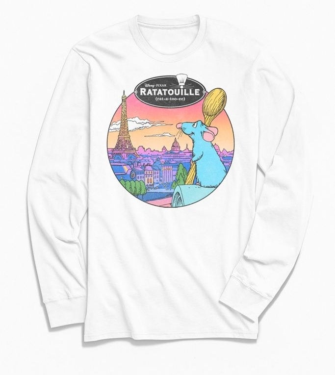 a white long sleeve shirt with remy from ratatouille on it holding a spoon and looking out at the city