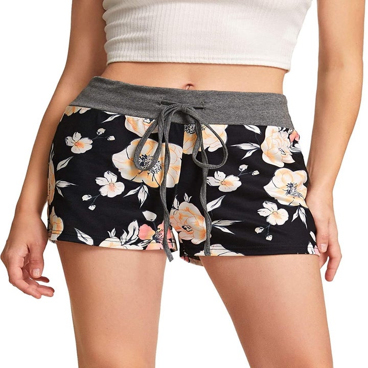 A model wearing the shorts with a black and peach floral print and a gray drawstring waistband
