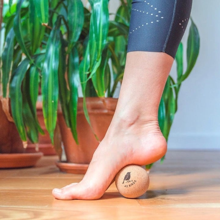 A person rolls the ball underneath the arch of their foot