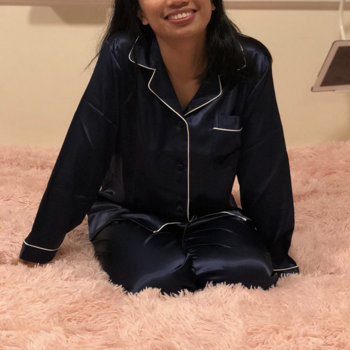 A reviewer wearing the navy pajama pants and matching buttoned-up long-sleeve pajama top with white trim 