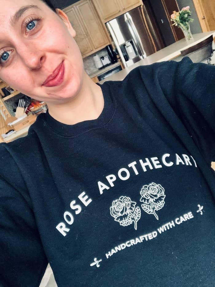 Abby (who wrote the review below) wearing her black sweatshirt that has the white Rose Apothecary logo from the show on it. It says "Rose Apothecary, handcrafted with care" and has two illustrated roses