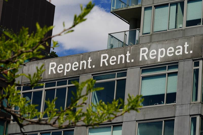 A view of a sign in New York City reading "Repent. Rent. Repeat."