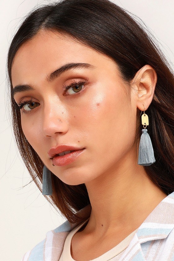 model wearing pastel blue tassel earrings with gold charm 