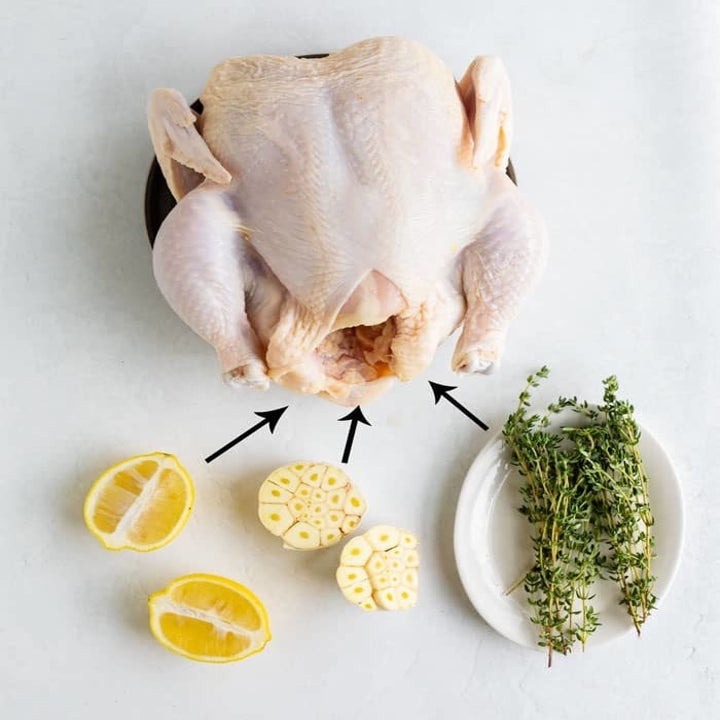 Preparing roast chicken with sliced lemon, garlic, and herbs.