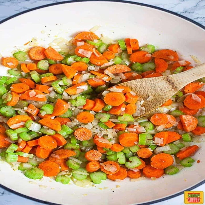 Vegetables being sautéd in a pot for chicken noodle soup.