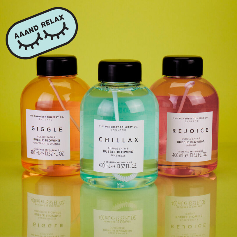 Three bottles of bubble bath with bubble blowing sticks inside of them, called Giggle, Chillax, and Rejoice 