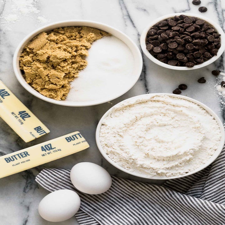 Butter, egg, flour, chocolate chips, and other ingredients for making chocolate chip cookie ingredients in bowls. 