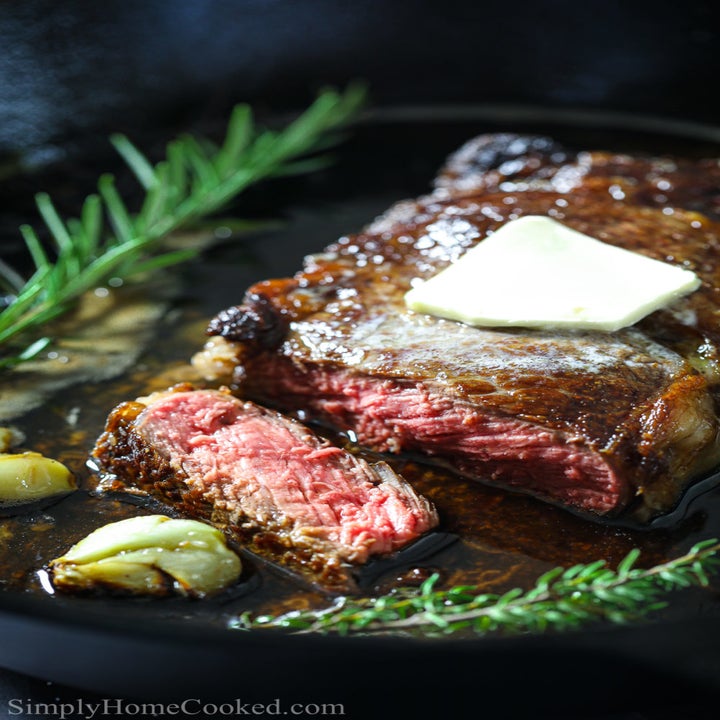 Medium-cooked steak with butter in a cast iron skillet.