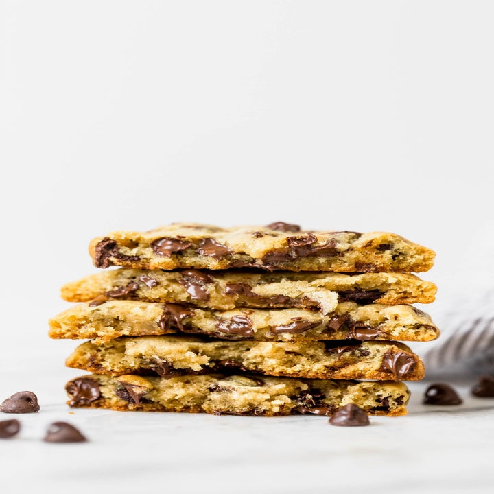A stack of gooey chocolate chip cookies, shown sliced in half.