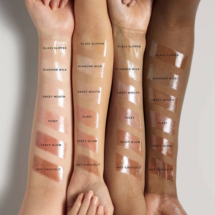 Six Fenty Gloss Bomb swatches on the arms of people with light, medium, tan, and deep skin tones