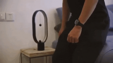A person connecting two magnetic balls attached by strings to turn on the lamp