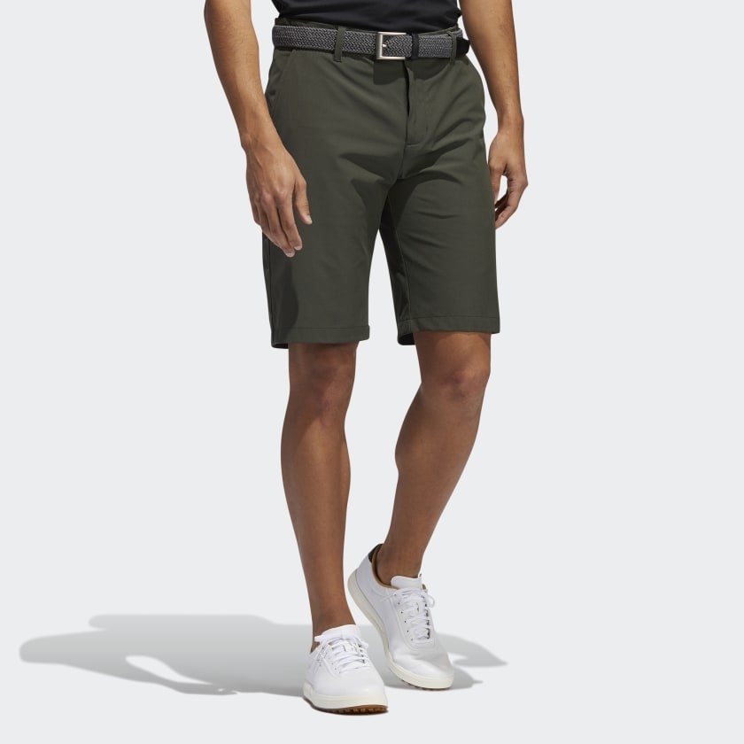 Dark green shorts that fall just above person&#x27;s knees, paired with belt and white sneakers