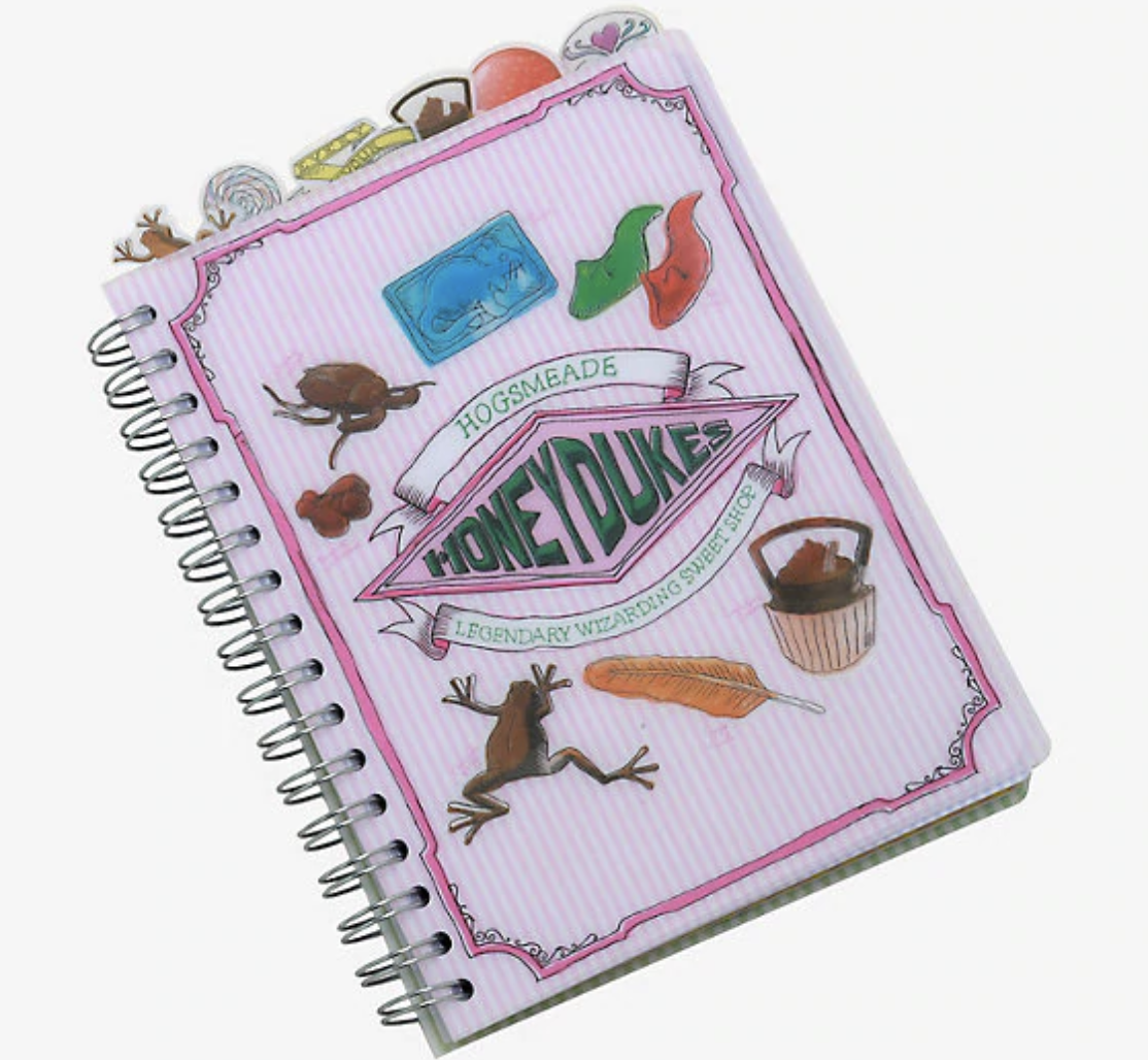 A notebook that says &quot;Hogsmeade Honeydukes: Legendary Wizarding Sweet Shop&quot; on the front with cartoon chocolate frog, candy quill, cauldron cake, and other candies, as well as candy-shaped notebook tabs popping out of the top for organization 