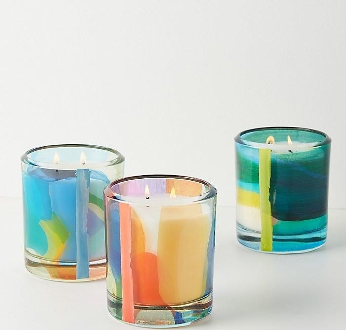 Three multicolored candles, each with two lit wicks, on a white background 