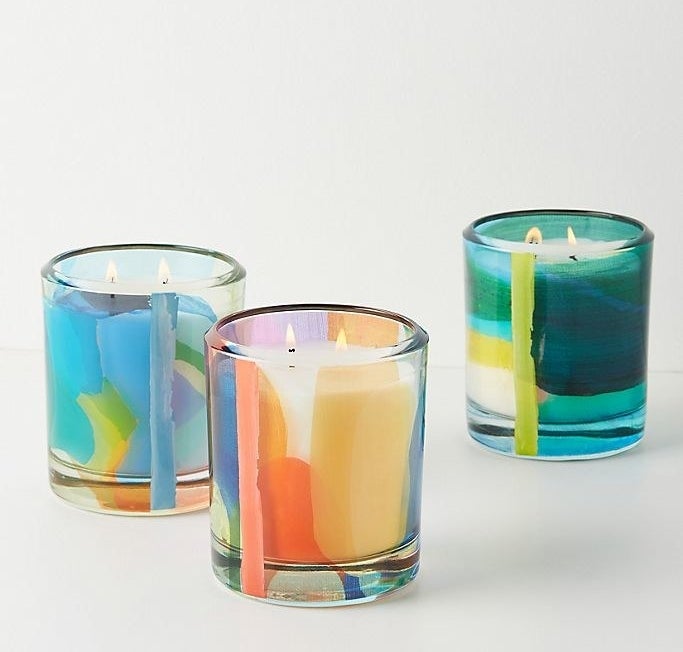 Three multicolored candles, each with two lit wicks, on a white background